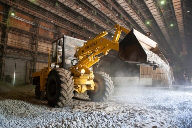 Yellow front-end loader dumping gravel at industrial worksite.