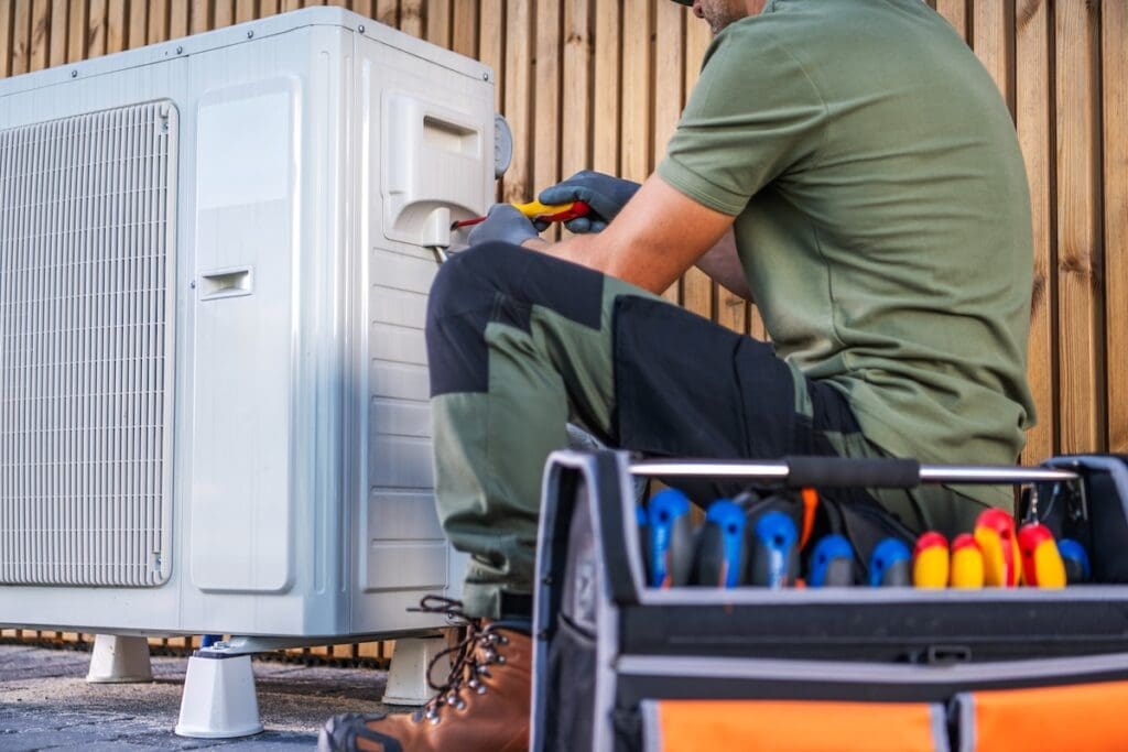 HVAC technician with tools working on outdoor unit